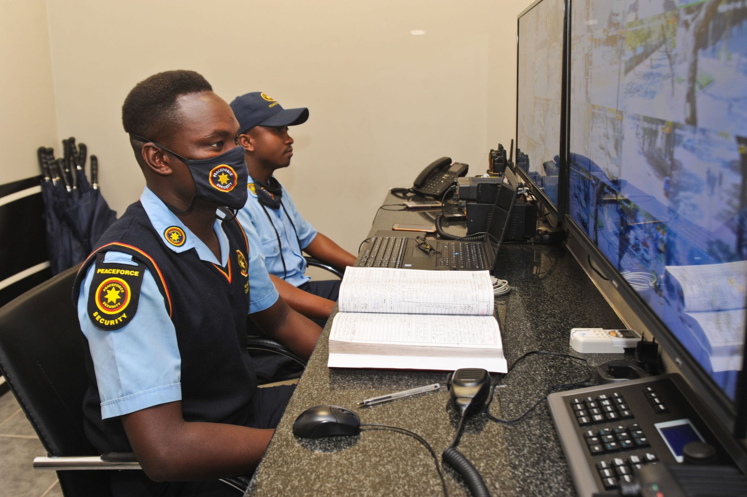 CCTV Technology Two security officers in Peaceforce uniforms monitoring security screens